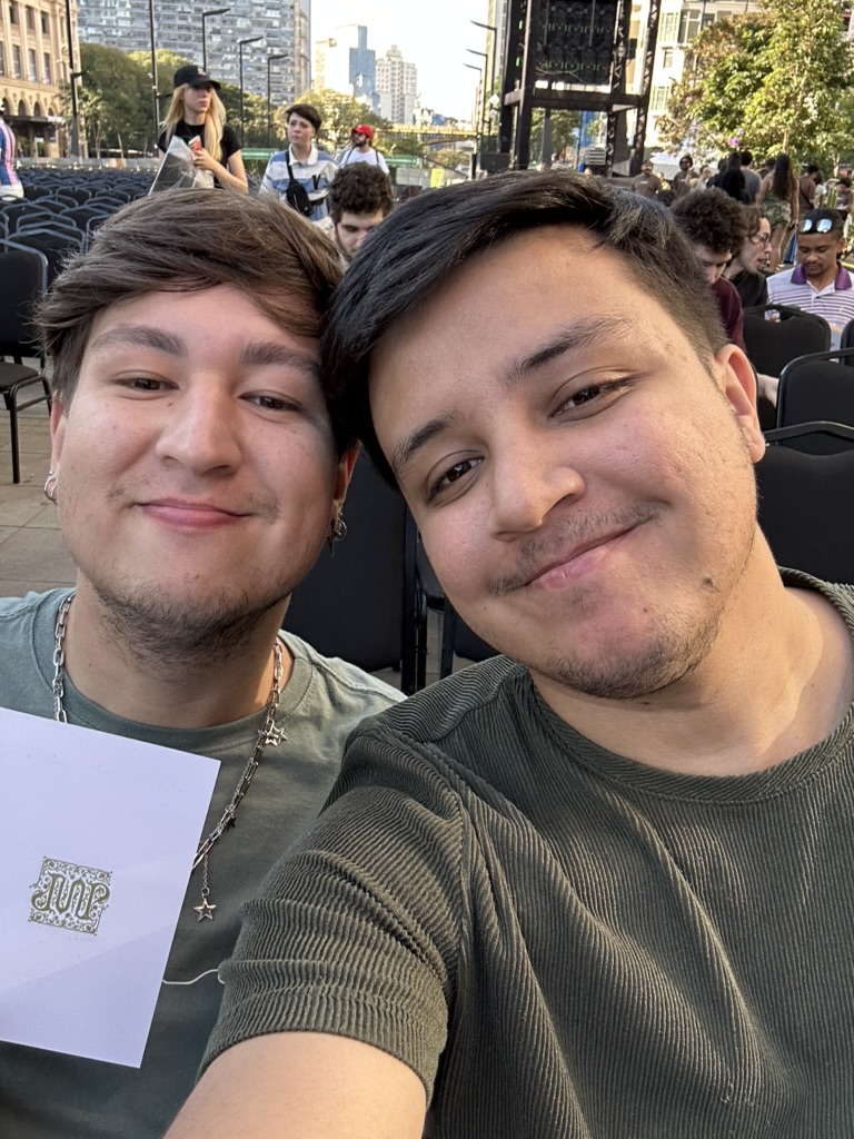 Wesley e Vinícius sorrindo juntos em um evento ao ar livre